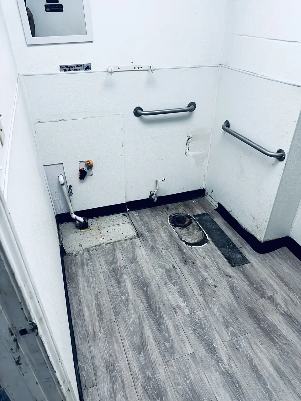 Before: gutted restroom with exposed plumbing