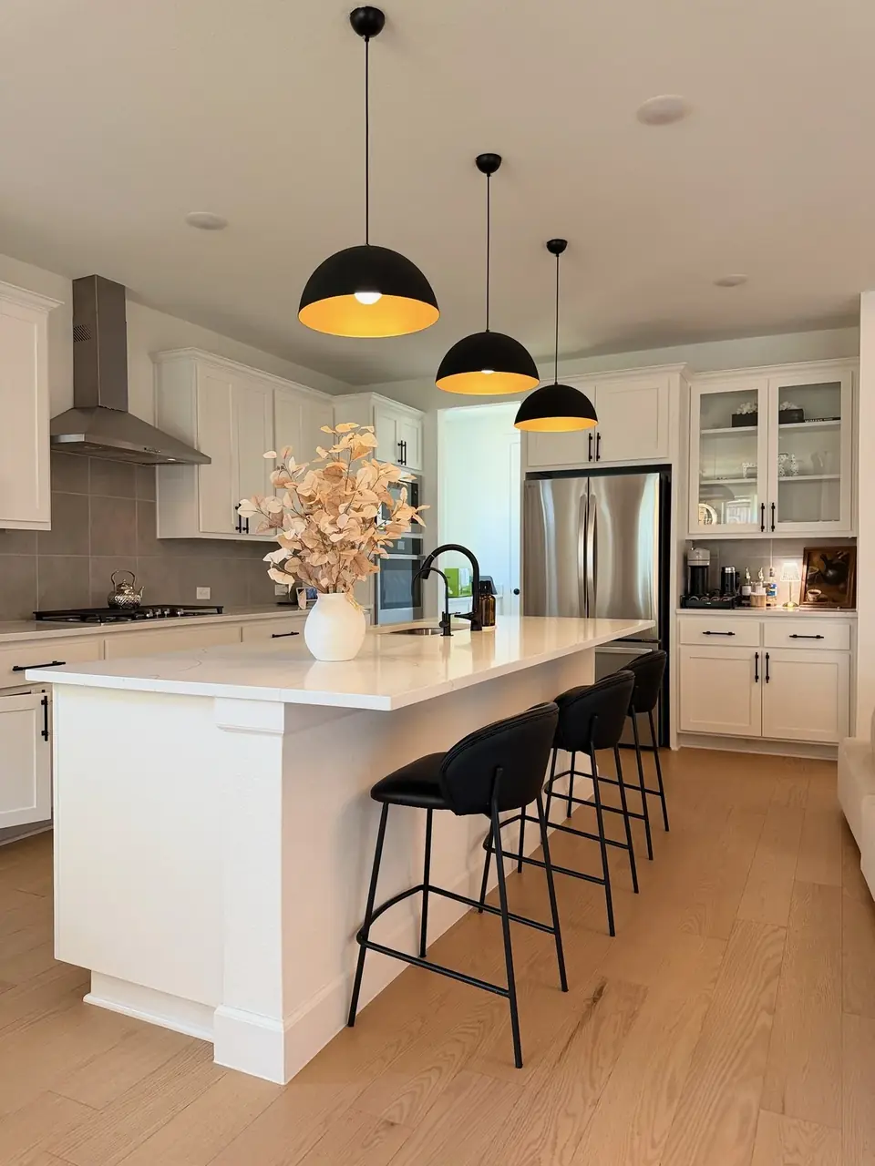Kitchen with white island, black dome pendants and black counter stools